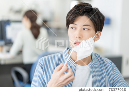 一個休閒風格的年輕商人，他在辦公室裡摘下面具微笑 78377018