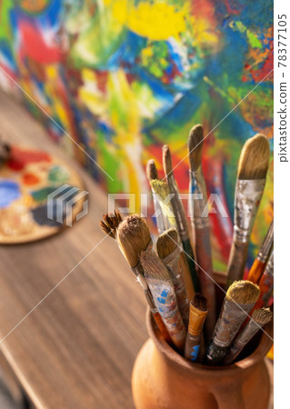 Paint brush in clay jug and palette on wooden table background. Oil painting and art still life 78377105
