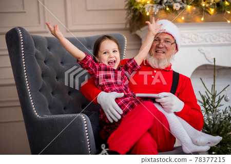 Santa Claus and child at home against Christmas tree. Family holiday concept Santa Claus and child at home against Christmas tree. Family holiday concept 78377215