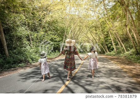 Mother and daughters walking in a park 78381879