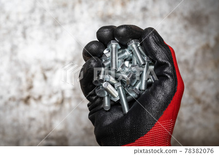 Person wearing protective glove holding handful of bolts Person wearing protective glove holding handful of bolts 78382076