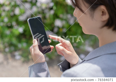 Up of the hand of a woman holding a smartphone in the park 78384071