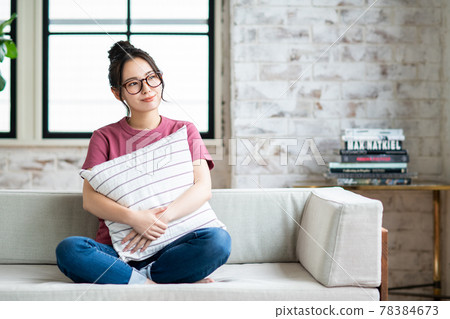 A young woman relaxing in the living room with a cushion A young woman relaxing in the living room with a cushion 78384673