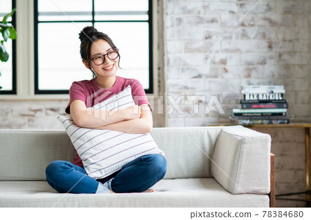 A young woman relaxing in the living room with a cushion A young woman relaxing in the living room with a cushion 78384680