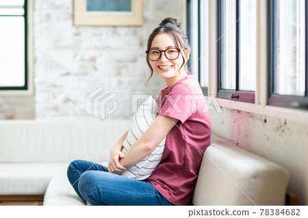 A young woman relaxing in the living room with a cushion A young woman relaxing in the living room with a cushion 78384682