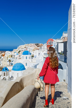 Young woman walks on the island of Santorini 78389097
