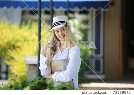 Beautiful blonde hair girl standing with confidence in front of flower in open retails flora shop. Small business owner concept. Beautiful blonde hair girl standing with confidence in front of flower in open retails flora shop. Small business owner concept. 78389972