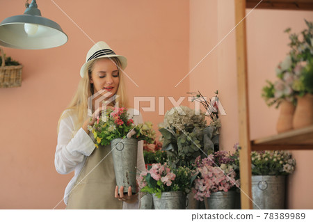 Beautiful blonde hair girl standing with confidence in front of flower in open retails flora shop. Small business owner concept. Beautiful blonde hair girl standing with confidence in front of flower in open retails flora shop. Small business owner concept. 78389989