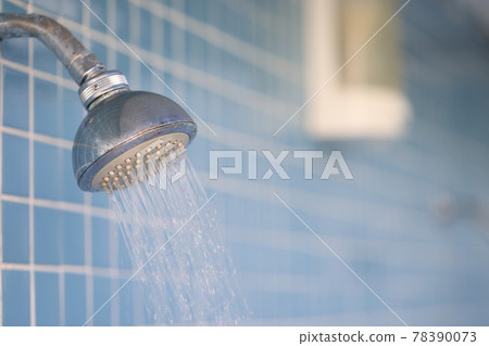 Water flows from rain shower in trickles into hotel bathroom 78390073