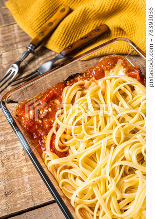 Oven roasted feta pasta with tomatoes in baking dish. Wooden background. Top view Oven roasted feta pasta with tomatoes in baking dish. Wooden background. Top view 78391036