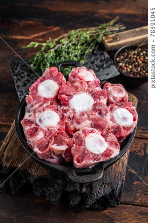 Raw veal beef Oxtail Meat on butcher wooden board with cleaver. Dark wooden background. Top view Raw veal beef Oxtail Meat on butcher wooden board with cleaver. Dark wooden background. Top view 78391045