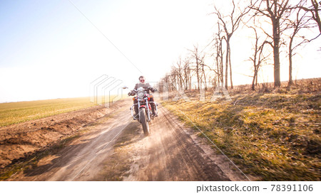 Young curly biker with red glasses drive ride on red chopper 78391106