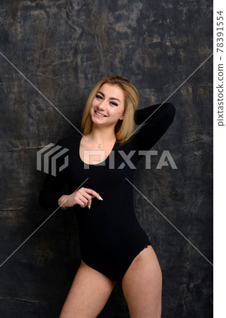 Young blonde plump woman with bright makeup in black bodysuit at dark background 78391554