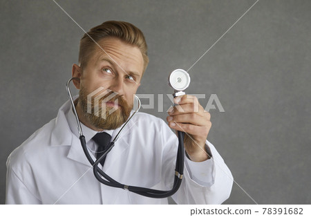 Portrait of male doctor holding stethoscope and listening to patient's heartbeat Portrait of male doctor holding stethoscope and listening to patient's heartbeat 78391682