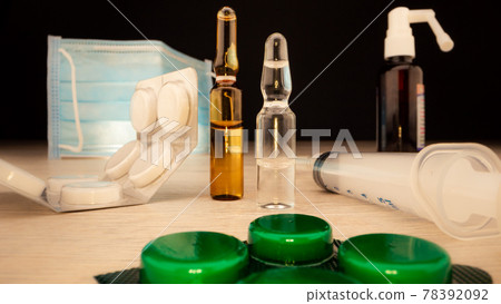 Green painkillers in plastic blister lie against syringe 78392092