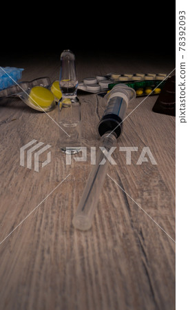 Transparent vial with vaccine stands on table against pills 78392093