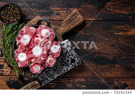 Raw veal beef Oxtail Meat on butcher wooden board with cleaver. Dark wooden background. Top view. Copy space 78392344
