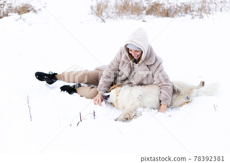 Young beautiful woman and her golden retriever dog having fun in winter. 78392381