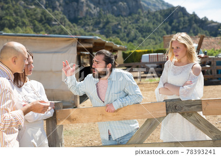 Displeased couples talking through wooden fence Displeased couples talking through wooden fence 78393241