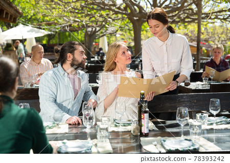 Charming young waiter and couple at open-air restaurant summer 78393242
