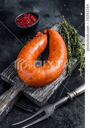 Bavarian Smoked sausage on a wooden rustic board with thyme. Black background. Top view Bavarian Smoked sausage on a wooden rustic board with thyme. Black background. Top view 78393564
