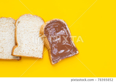 Bread with sweet chocolate hazelnut on yellow background. Bread with sweet chocolate hazelnut on yellow background. 78393852