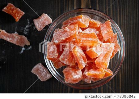 Natural farm homemade candied pumpkin fruits sprinkled with powdered sugar in a glass bowl on a wooden table, top view. Natural farm homemade candied pumpkin fruits sprinkled with powdered sugar in a glass bowl on a wooden table, top view. 78396842