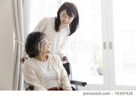 Young woman pushing a senior woman's wheelchair 78397426