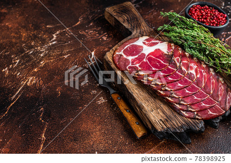 Sliced cured coppa ham on wooden board with thyme. Dark background. Top view. Copy space 78398925