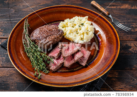 Sliced fillet mignon or tenderloin beef steak on a rustic plate with mashed potato. Dark wooden background. Top view 78398934