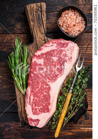Raw new york strip beef steak or striploin on a wooden board. Dark wooden background. Top view Raw new york strip beef steak or striploin on a wooden board. Dark wooden background. Top view 78398961