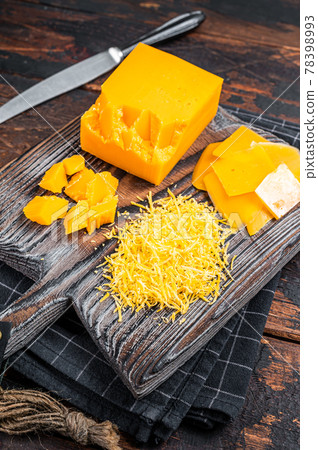 Grated and diceded Cheddar Cheese on a wooden chopping board. Dark wooden background. Top view 78398993