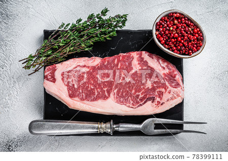 Raw striploin or new york strip steak on a marble board. White background. Top view 78399111