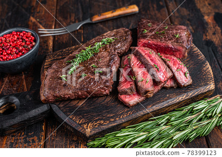 Grilled sliced skirt beef meat steak on a cutting board with herbs. Dark wooden background. Top view Grilled sliced skirt beef meat steak on a cutting board with herbs. Dark wooden background. Top view 78399123