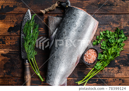 Big piece of Raw cut salmon fish on a wooden cutting board with chef knife. Dark Wooden background. Top view Big piece of Raw cut salmon fish on a wooden cutting board with chef knife. Dark Wooden background. Top view 78399124