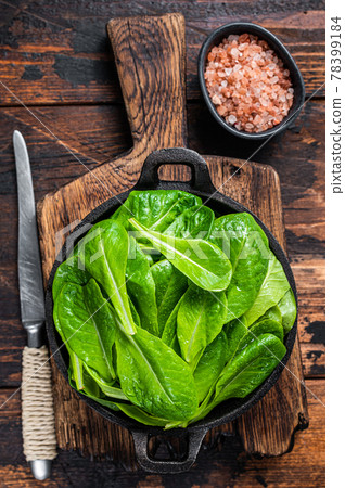 Baby romain green salad leaves in pan. Dark wooden background. Top view 78399184