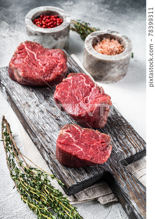 Fillet mignon beef raw steaks on a wooden board with salt and pepper. White background. Top view 78399311