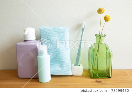 Bathroom bottles, shower towel, toothbrush, vase of plant on wooden table. white wall background. Skin care and spa concept Bathroom bottles, shower towel, toothbrush, vase of plant on wooden table. white wall background. Skin care and spa concept 78399480