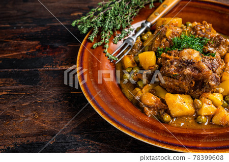 Lamb oxtails ragout with vegetables in a rustic plate. Dark wooden background. Top view. Copy space Lamb oxtails ragout with vegetables in a rustic plate. Dark wooden background. Top view. Copy space 78399608