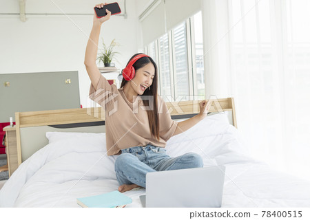 Relax woman holding book read on bed using headphone listen music. Young woman relaxation reading open book leisure mind. Happiness beautiful woman person Relax woman holding book read on bed using headphone listen music. Young woman relaxation reading open book leisure mind. Happiness beautiful woman person 78400515