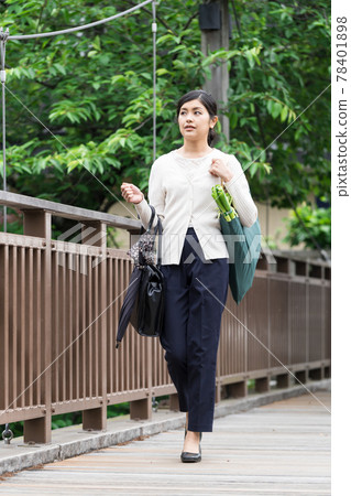 A business woman walking with an eco bag down from her shoulder A business woman walking with an eco bag down from her shoulder 78401898