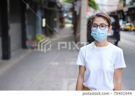 Woman wearing medical face mask during walking in street footpath and night market, prevent coronavirus or Corona Virus Disease (Covid-19). Health, life concept 78401944