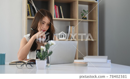 Confident businesswoman watching webinar on laptop computer while sitting in modern office. Confident businesswoman watching webinar on laptop computer while sitting in modern office. 78402381