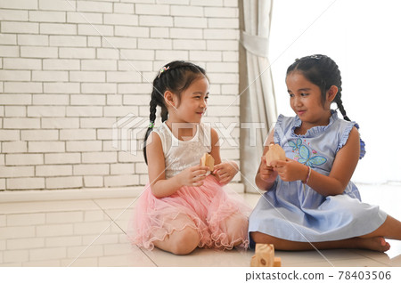Two kids play with toy blocks on the floor of the children's room. 78403506