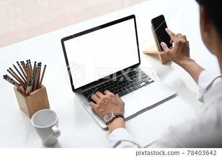Croped shot of business woman using smartphone and laptop with white screen on work space. Croped shot of business woman using smartphone and laptop with white screen on work space. 78403642