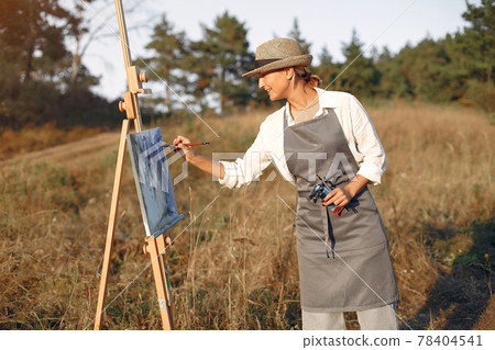 Woman in a apron painting in a field Woman in a apron painting in a field 78404541