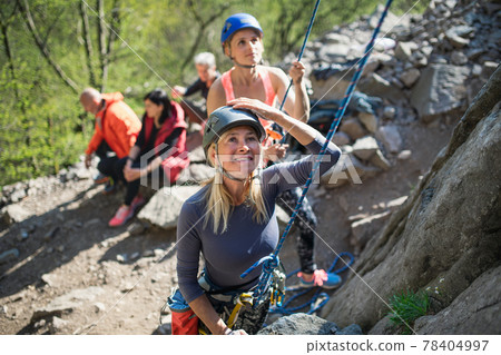 Group of seniors with instructor climbing rocks outdoors in nature, active lifestyle. Group of seniors with instructor climbing rocks outdoors in nature, active lifestyle. 78404997