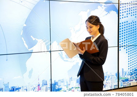 A young woman taking notes in her personal organizer in front of a large display A young woman taking notes in her personal organizer in front of a large display 78405801