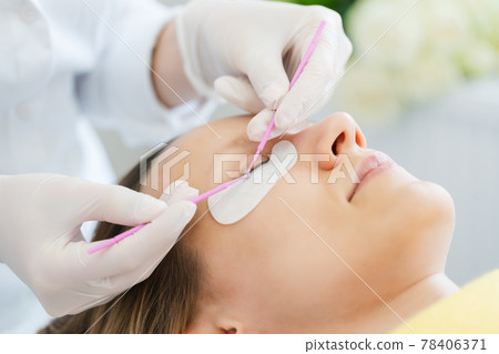 Woman receiving eyelash extension in salon 78406371