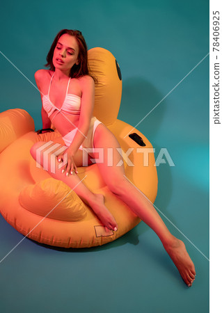 Woman in white swimsuit sitting on yellow air mattress Woman in white swimsuit sitting on yellow air mattress 78406925